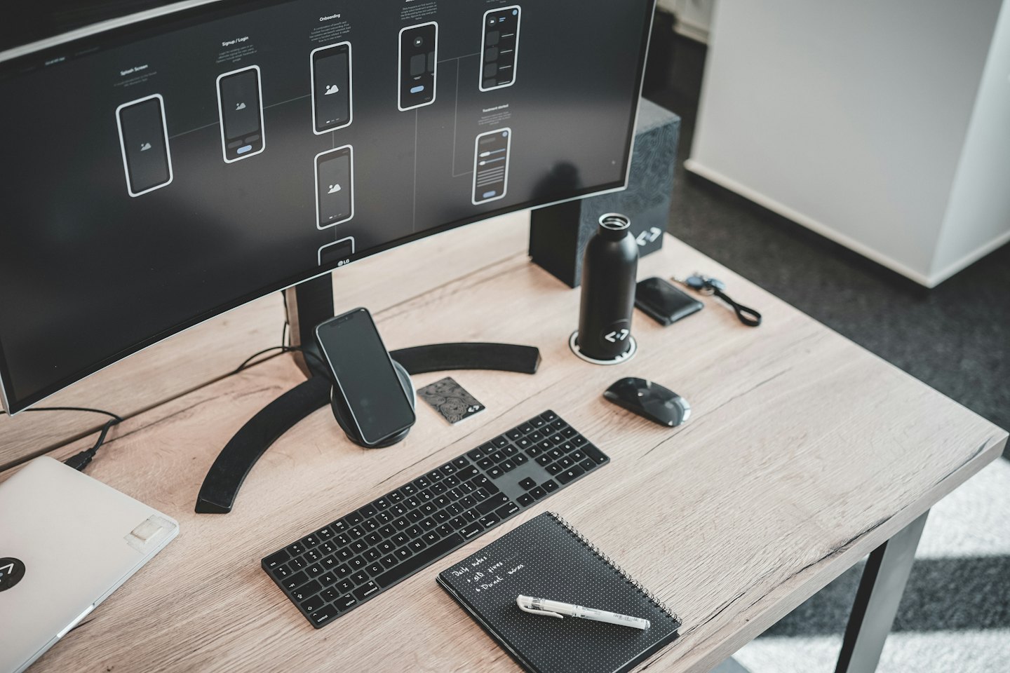 Designer's modern desk with monitor showing app wireframes.
