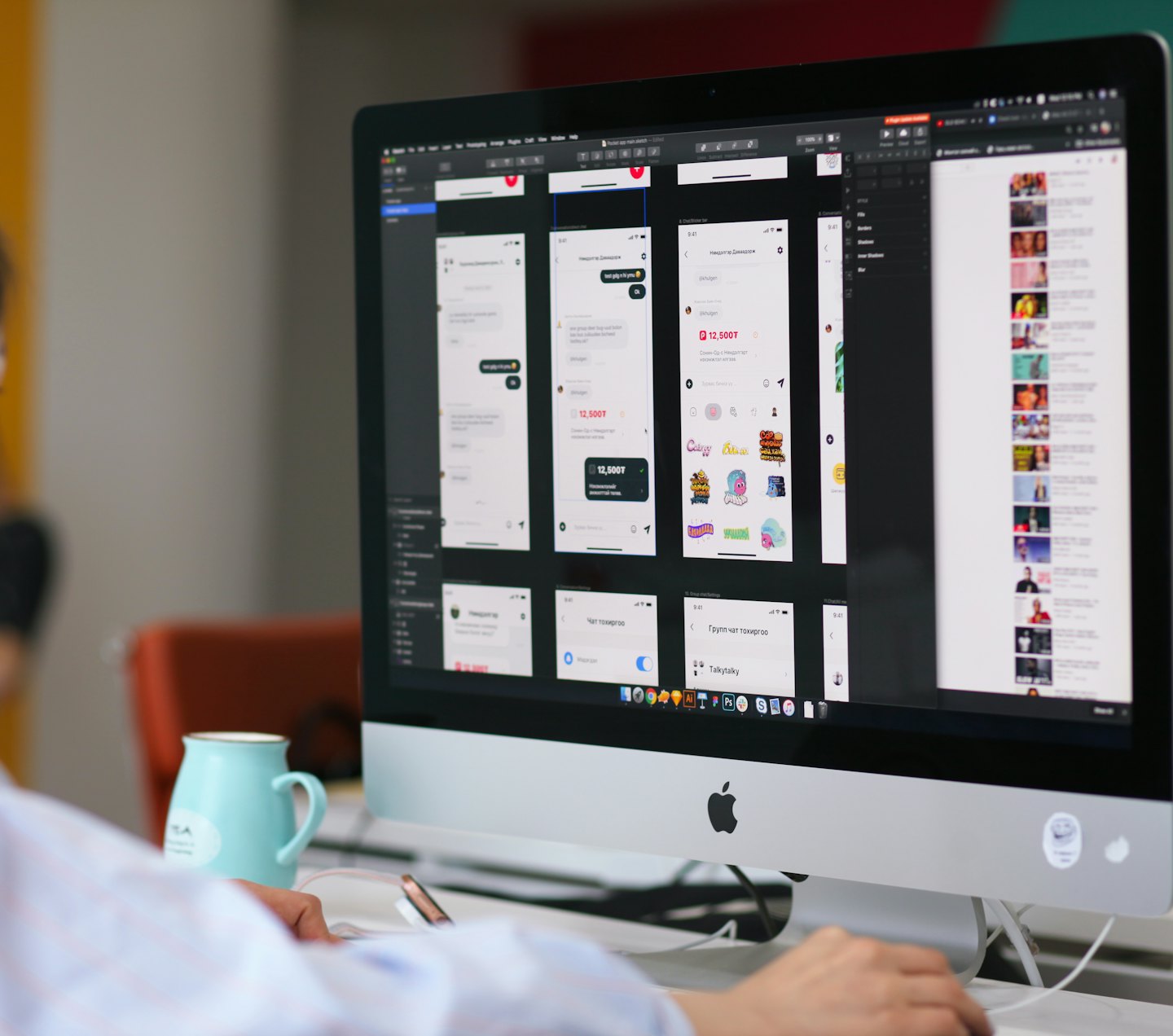 Person designing app wireframes on a desktop computer with a teal mug.